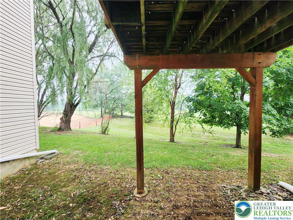 8513 Gateway Road Breinigsville, PA 18031 - Photo 43 of 45 A spacious backyard unfolds, shaded by mature trees, with a large deck providing an elevated outdoor living area.