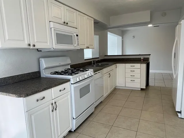 a kitchen with granite countertop white cabinets and appliances