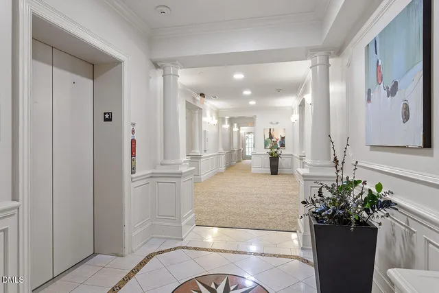 a lobby with a potted plant and a large mirror