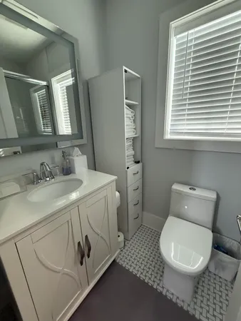 a bathroom with a granite countertop toilet sink and mirror