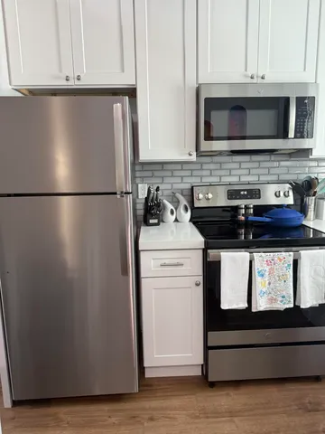 a kitchen with stainless steel appliances granite countertop a refrigerator stove a microwave and cabinets