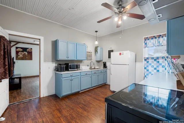 a kitchen with a refrigerator a stove top oven a dining table and chairs