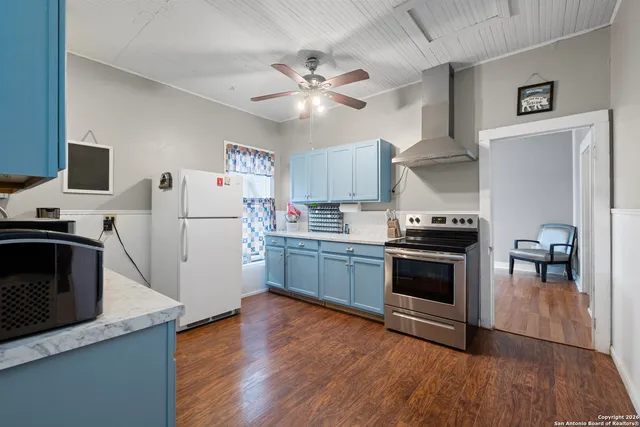 a kitchen with granite countertop a refrigerator stove and wooden floor