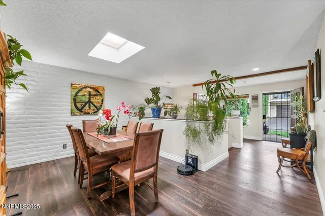 a view of a dining room with furniture one side kitchen view and wooden floor
