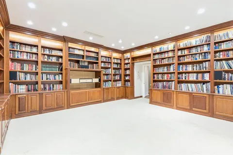 a view of an empty room with a bookshelf and a large window