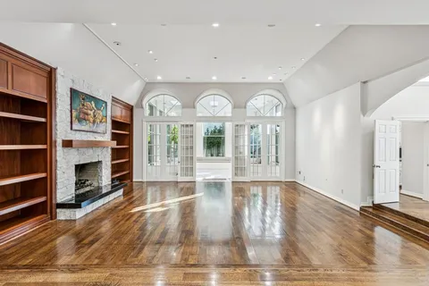 a view of an empty room with window and wooden floor