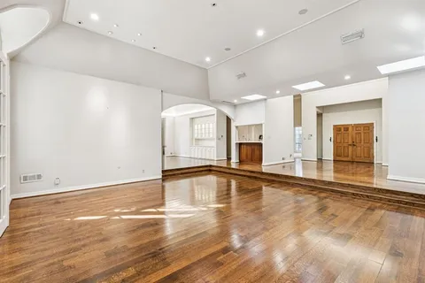 a view of an empty room with window and wooden floor