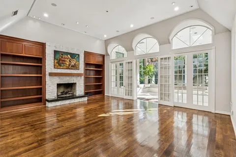 a view of an empty room with wooden floor fireplace and a window