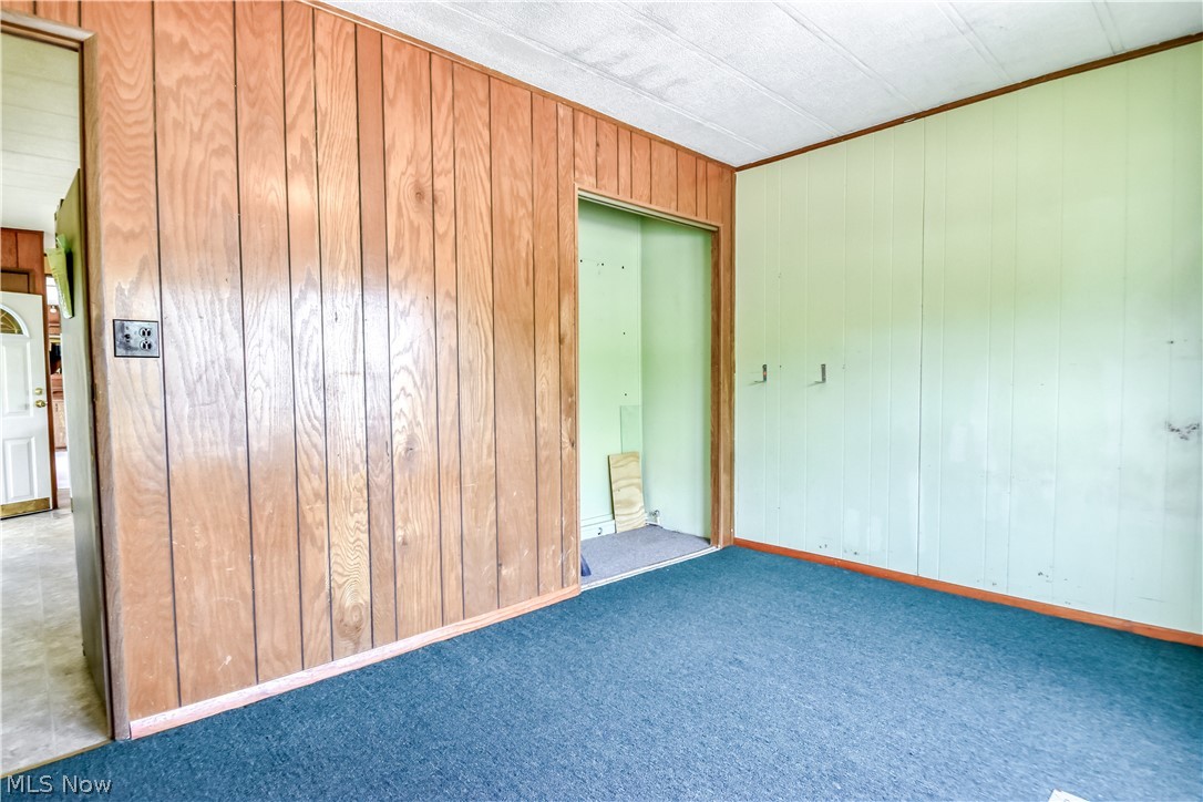 112 Lakeside Way Southwest Warren, OH 44481 - Photo 12 of 16 Room featuring dark blue carpet flooring, wood paneling, and light green paneling