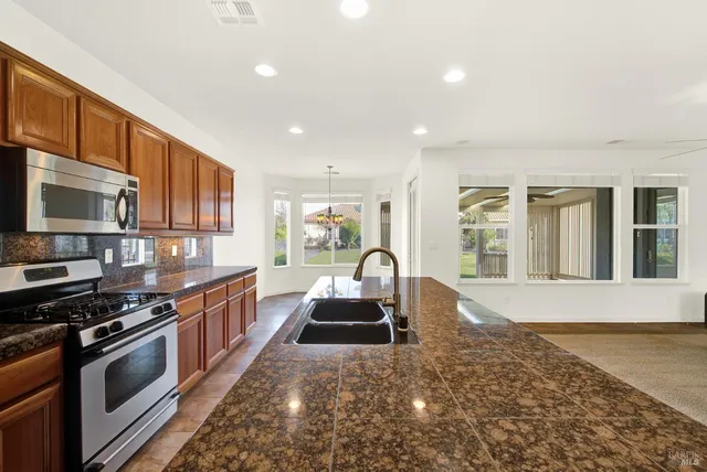 a view of a kitchen with granite countertop a sink and a stove