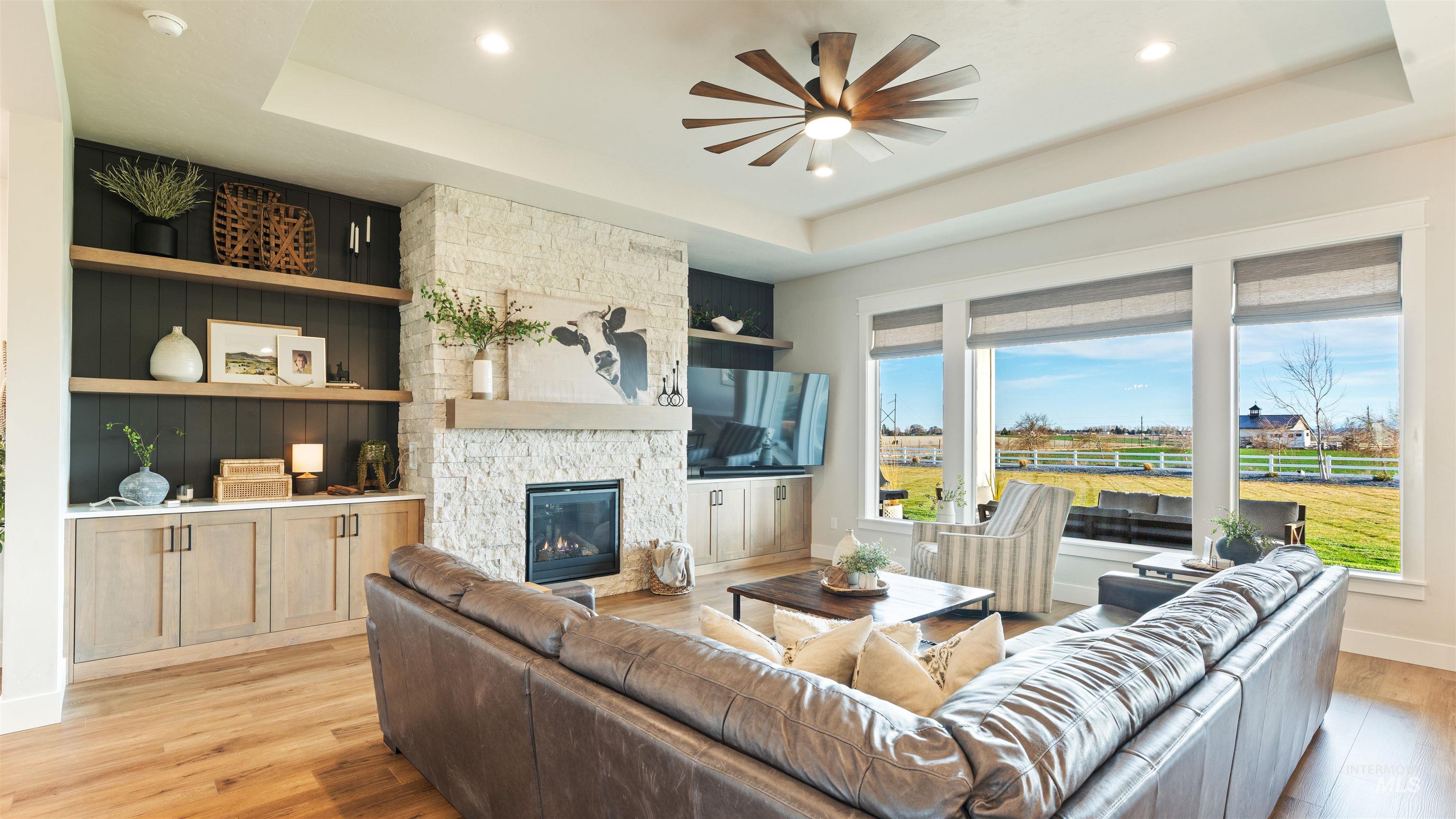 16901 Spring Meadow Drive Caldwell, ID 83607 - Photo 12 of 50 Living room featuring a raised ceiling, light wood-style flooring, a ceiling fan, a fireplace, and recessed lighting
