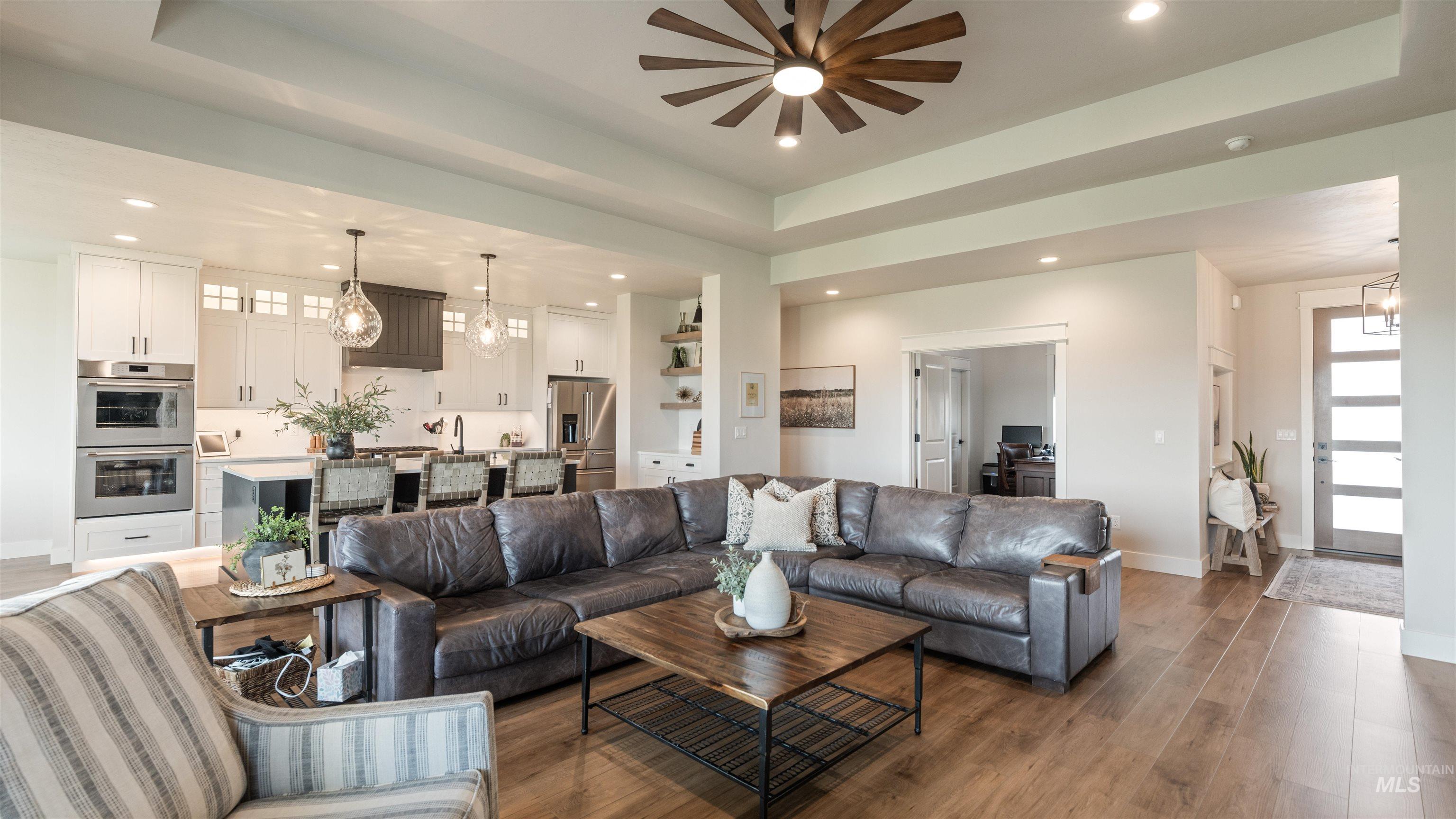 16901 Spring Meadow Drive Caldwell, ID 83607 - Photo 14 of 50 Living room with a tray ceiling, light wood finished floors, suspended lighting, and ceiling fan