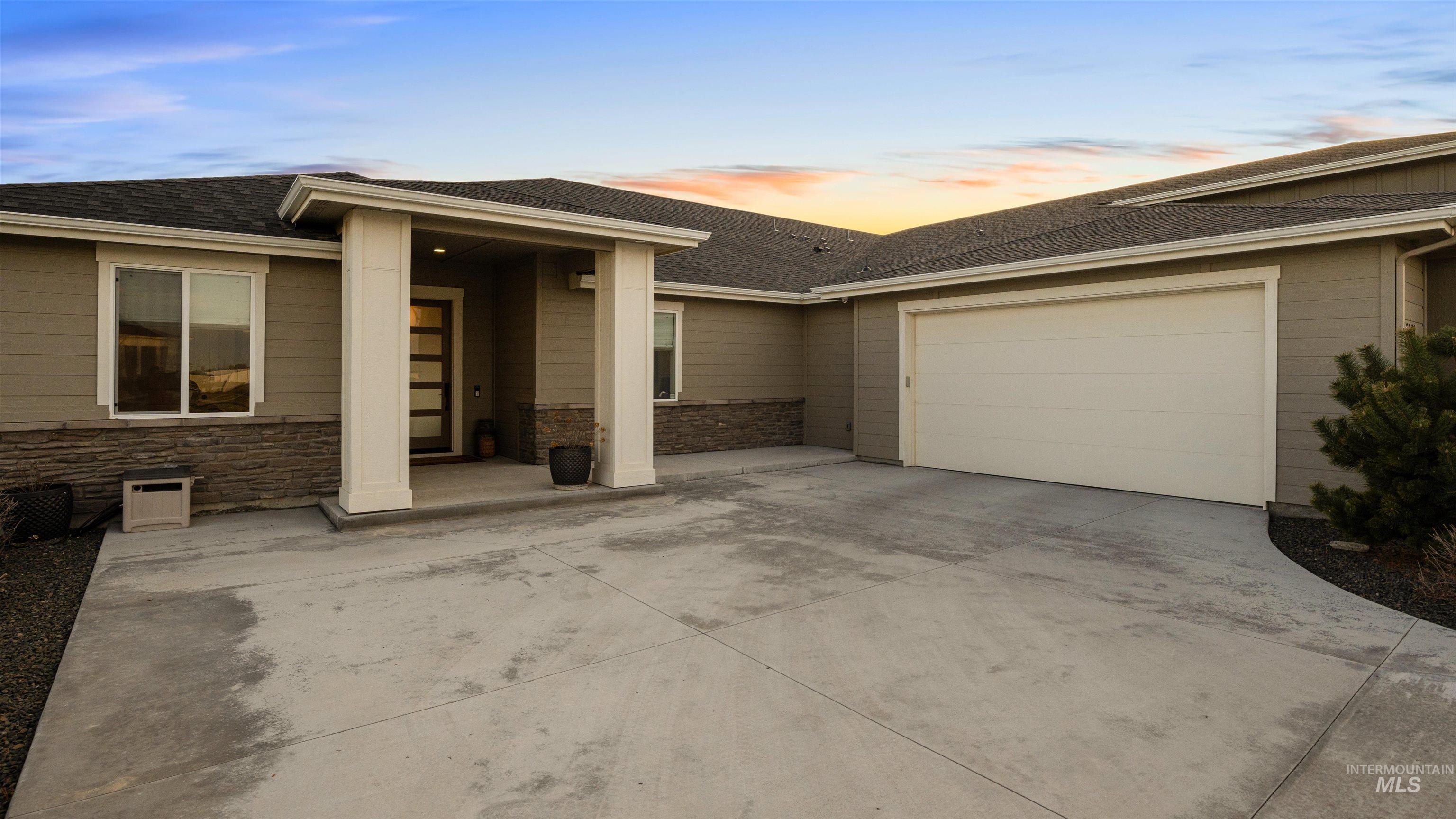 16901 Spring Meadow Drive Caldwell, ID 83607 - Photo 6 of 50 View of front of home featuring driveway, roof with shingles, stone siding, and an attached garage