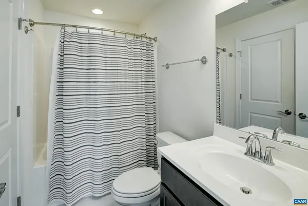 a bathroom with a sink a toilet a mirror and shower curtain