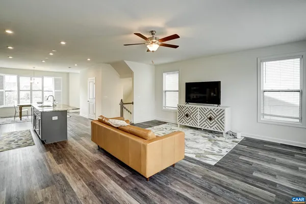 a living room with couches flat screen tv and couches with wooden floor
