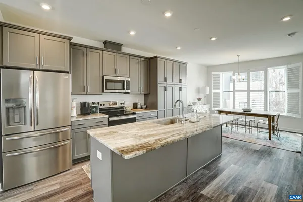 a kitchen with kitchen island a counter top space a sink stainless steel appliances and cabinets
