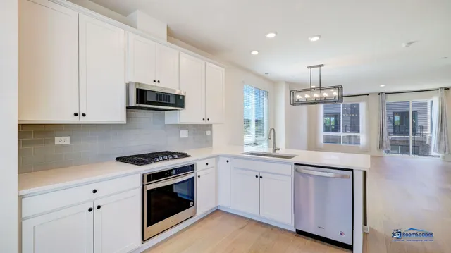 a kitchen with granite countertop white cabinets and stainless steel appliances
