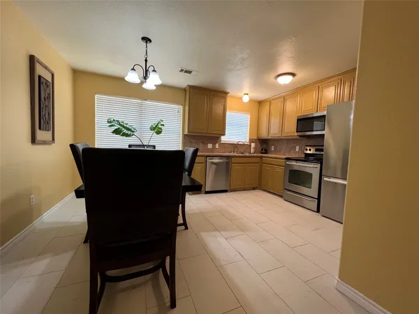a kitchen with stainless steel appliances granite countertop a stove top oven a sink dishwasher and a refrigerator