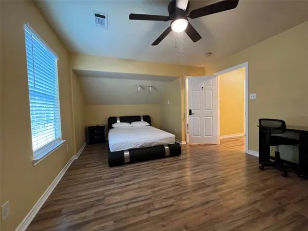 a spacious bedroom with a bed and wooden floor