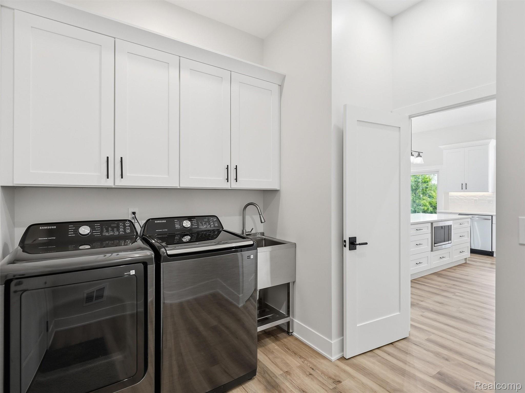 77850 Angling Road Richmond, MI 48062 - Photo 36 of 54 Dedicated laundry area featuring white shaker-style cabinetry with matte black hardware, a stainless steel utility sink with a gooseneck faucet, and wood-finish flooring