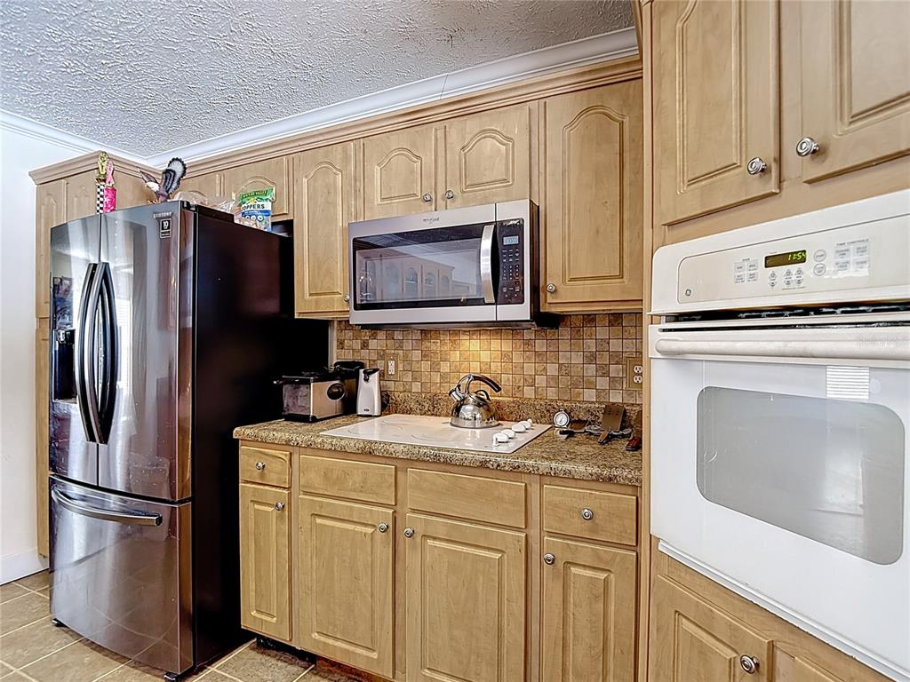 15821 Archer Street Hudson, FL 34667 - Photo 28 of 77 a kitchen with stainless steel appliances granite countertop a refrigerator stove and white cabinets