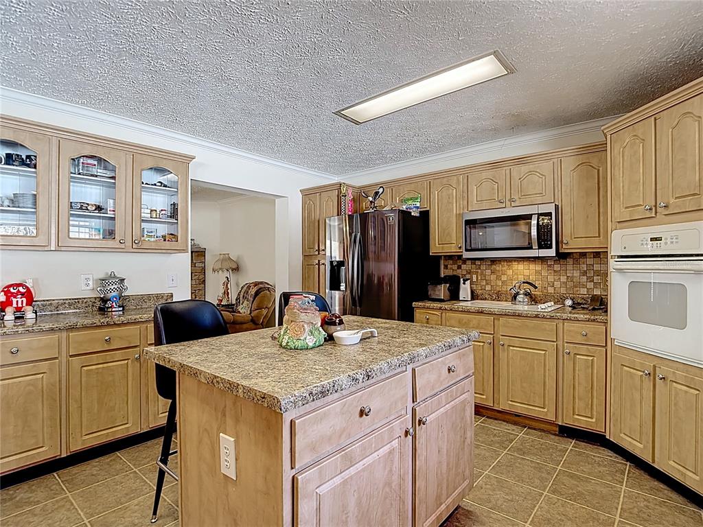15821 Archer Street Hudson, FL 34667 - Photo 29 of 77 a kitchen with stainless steel appliances granite countertop a stove top oven a sink dishwasher and a refrigerator with wooden cabinets