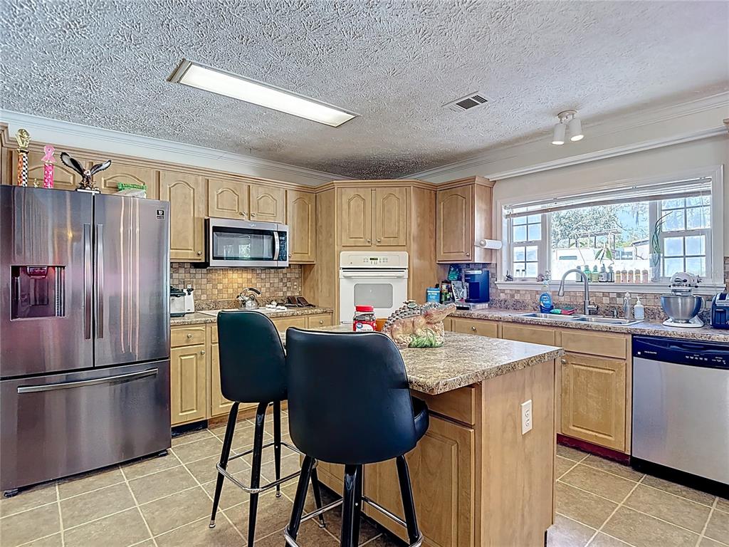 15821 Archer Street Hudson, FL 34667 - Photo 31 of 77 a kitchen with stainless steel appliances granite countertop a refrigerator a sink a stove a dining table and chairs
