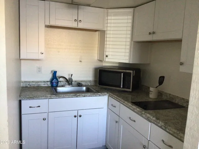 a kitchen with granite countertop white cabinets and a sink