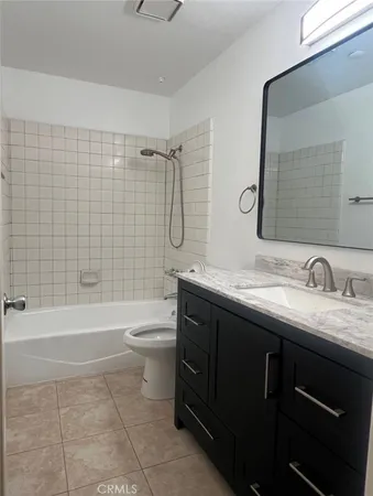 a bathroom with a granite countertop sink toilet mirror and bathtub