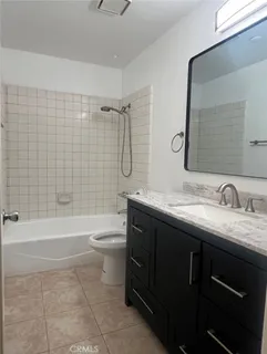 a bathroom with a granite countertop sink toilet mirror and bathtub