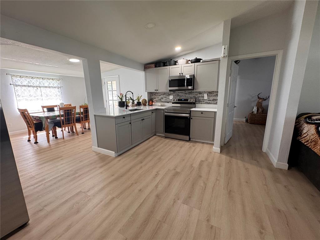 125 Ridgewood Drive Arcadia, FL 34266 - Photo 9 of 31 a kitchen with stainless steel appliances kitchen island granite countertop a stove top oven a sink a dining table and chairs with wooden floor