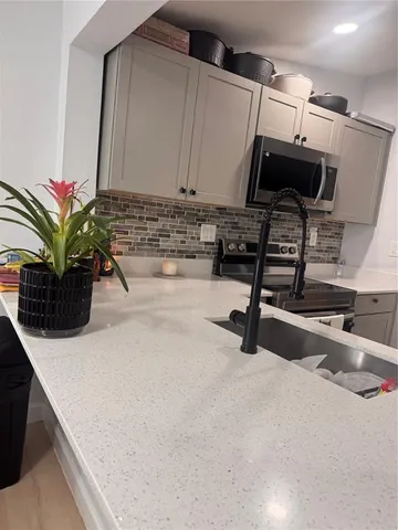 a kitchen with stainless steel appliances a sink a microwave a stove and white cabinets