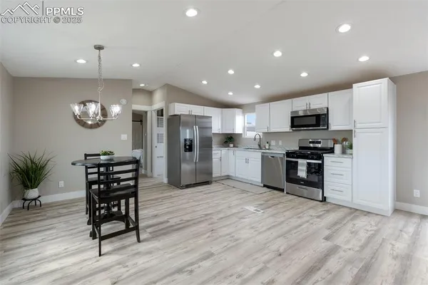 a kitchen with stainless steel appliances granite countertop a stove top oven a refrigerator and a sink