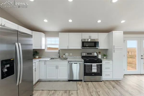 a kitchen with granite countertop a sink stainless steel appliances and cabinets