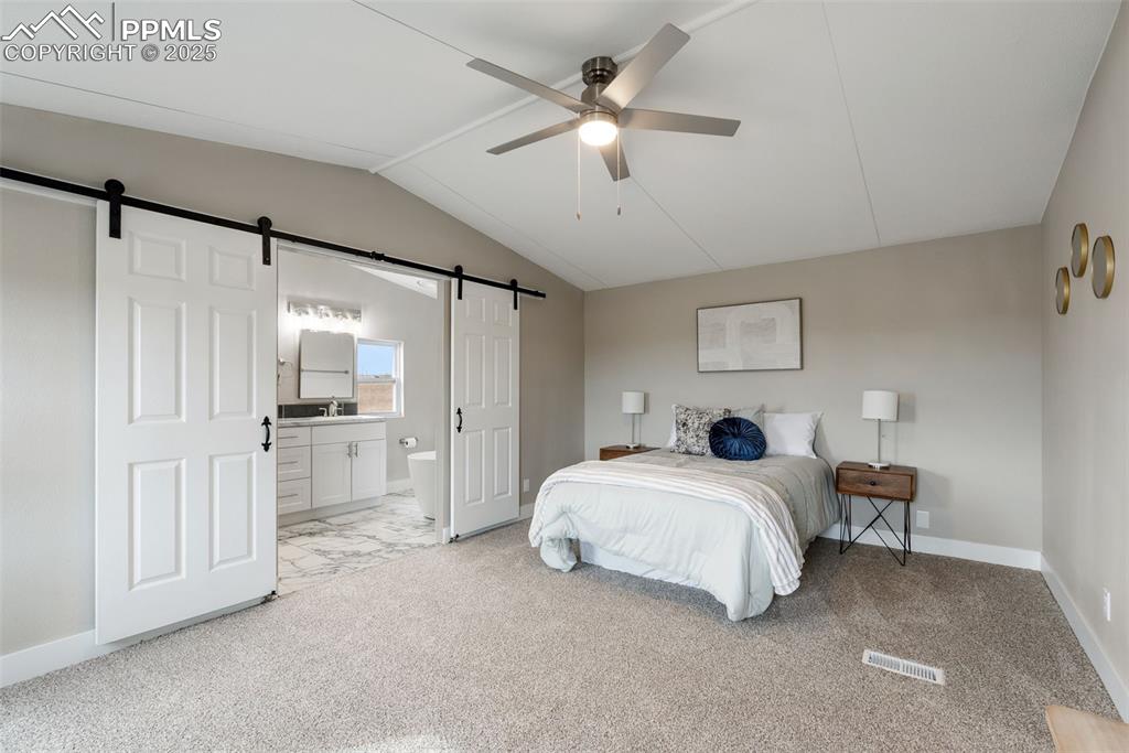 6190 Night Train Lane Yoder, CO 80864 - Photo 18 of 35 a spacious bedroom with a bed and a chandelier