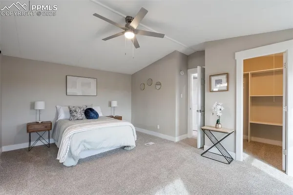 a spacious bedroom with a large bed a chandelier and windows