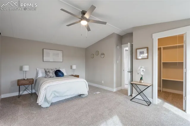 a spacious bedroom with a large bed a chandelier and windows