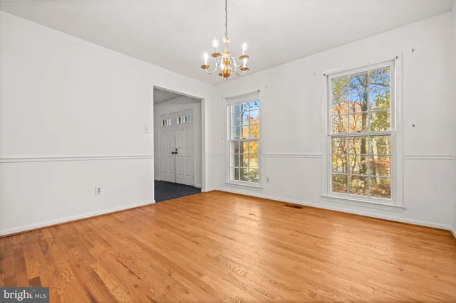 a view of an empty room with window and wooden floor