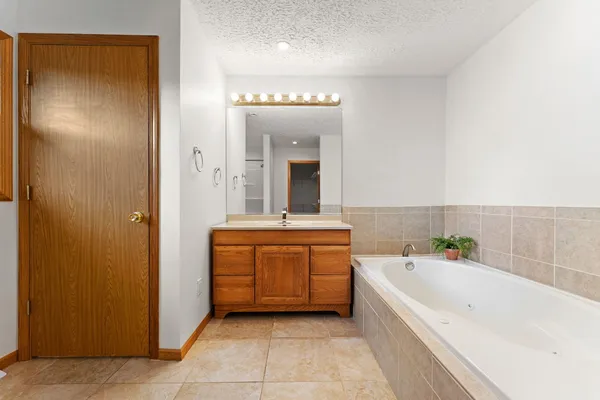 a bathroom with a bathtub a mirror a sink and vanity