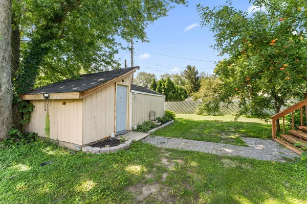 a view of backyard with large tree and wooden fence