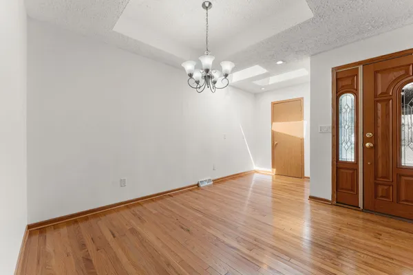 a view of an empty room with window and wooden floor