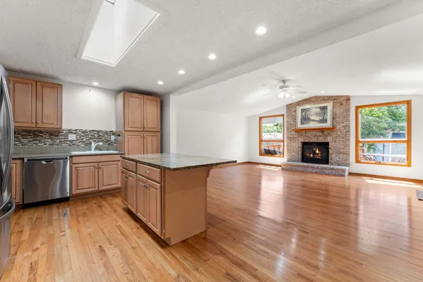 a kitchen with granite countertop a stove top oven a sink dishwasher and a refrigerator with wooden floor