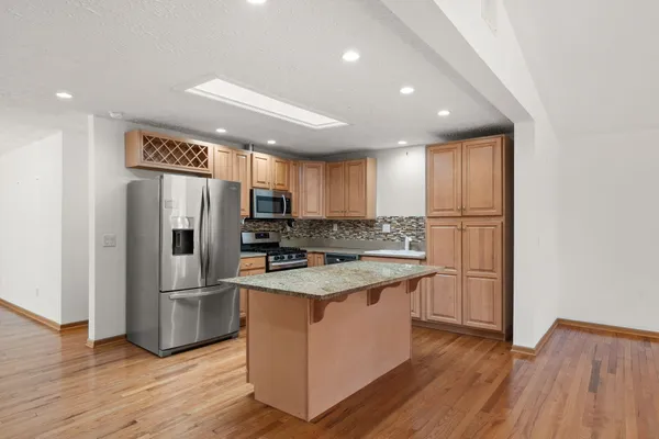 a kitchen with stainless steel appliances granite countertop a refrigerator a stove and a wooden floors