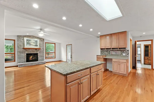 a kitchen with kitchen island granite countertop wooden floors and wide window