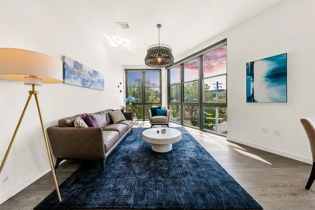 a living room with stainless steel appliances granite countertop furniture a large window with wooden floor