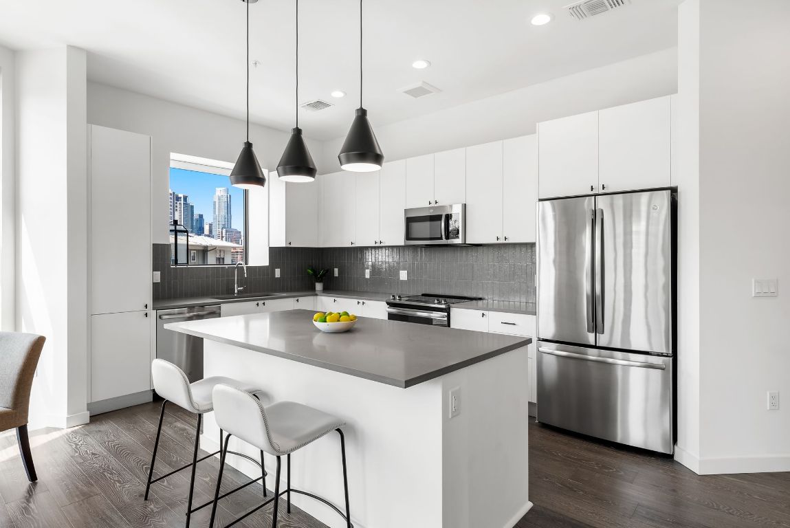 800 Embassy Drive, Unit 337 Austin, TX 78702 - Photo 4 of 29 a kitchen with stainless steel appliances granite countertop a refrigerator a sink a stove a microwave a center island and a cabinets