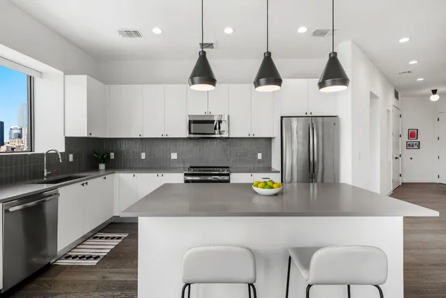 a kitchen with stainless steel appliances granite countertop a refrigerator a sink a stove a microwave a center island and a cabinets