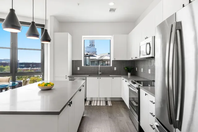 a kitchen with stainless steel appliances a sink a stove a refrigerator a center island and chairs