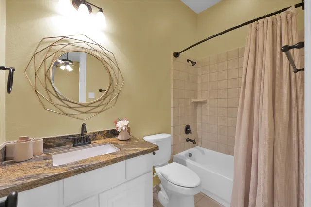 a bathroom with a granite countertop sink a toilet and a mirror