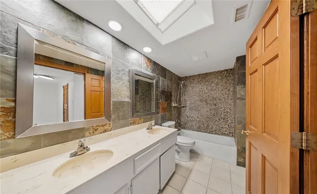 a bathroom with a granite countertop sink a toilet a mirror and shower